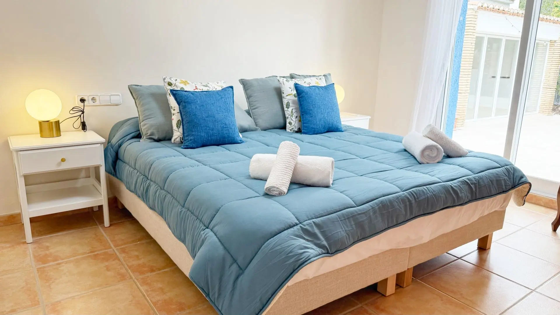 Kingsize Bett blaue Kissen zusammengerollte Handtücher Nachttisch runde Tischlampen